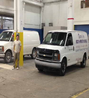 Picture of Jake and 2 of our vans inside our shop scaled